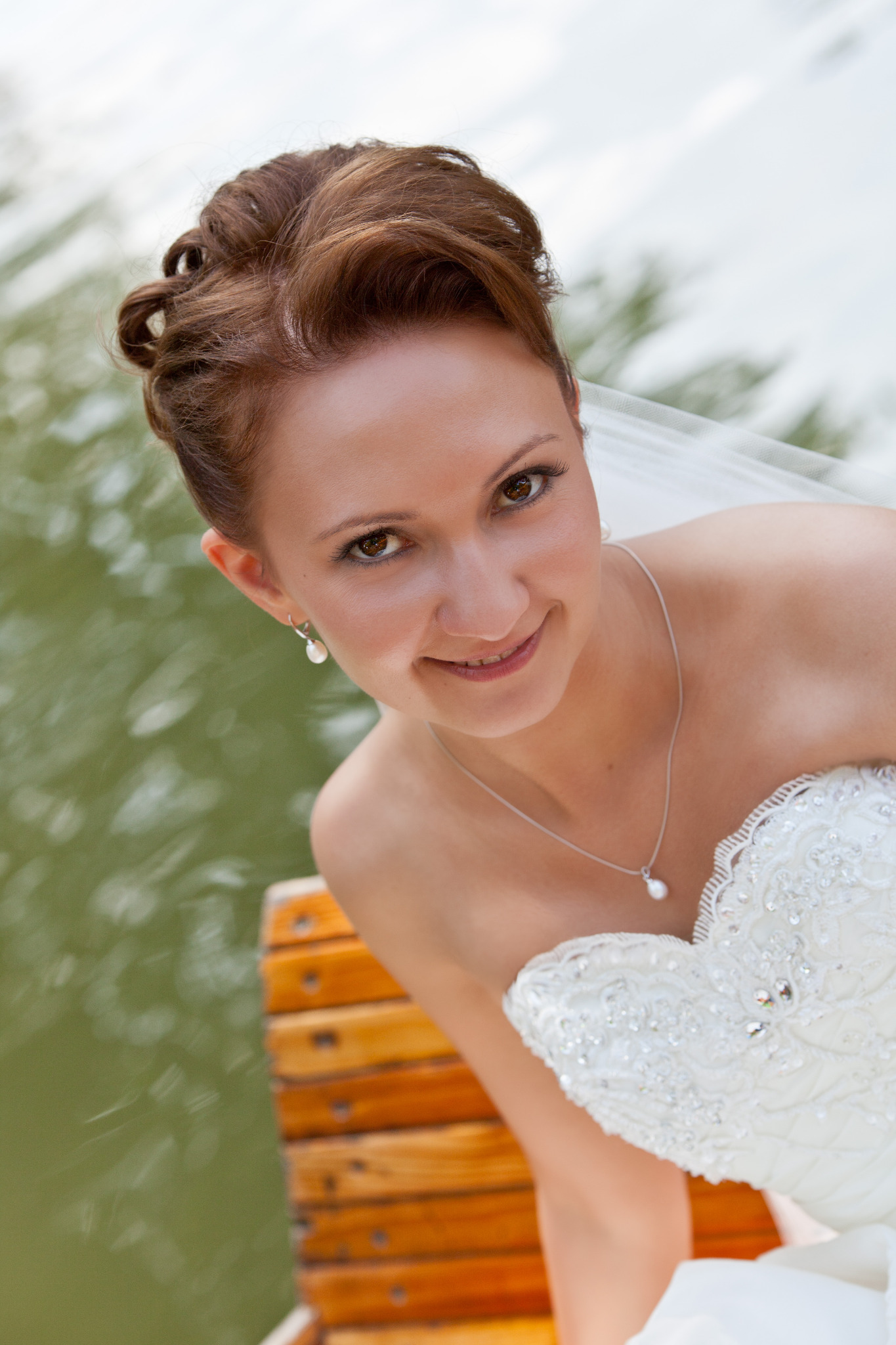 Braut mit Hochsteckfrisur und Make-up am Wasser